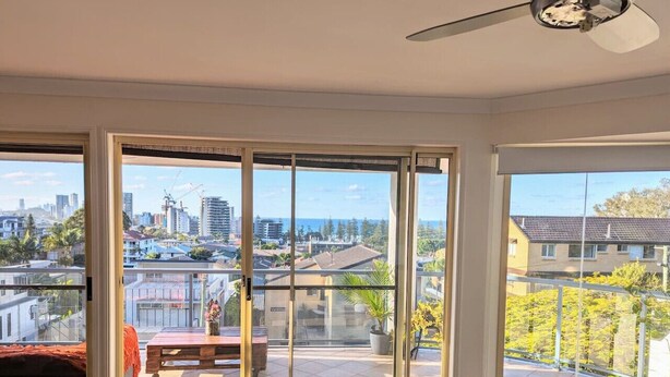 A room with a sliding glass door leading to a balcony with a city view. - Burleigh Breeze Coastal (Burleigh Heads)