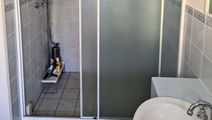 A shower with a glass door, a white sink, and tiled walls. - Burleigh Breeze Coastal (Burleigh Heads)