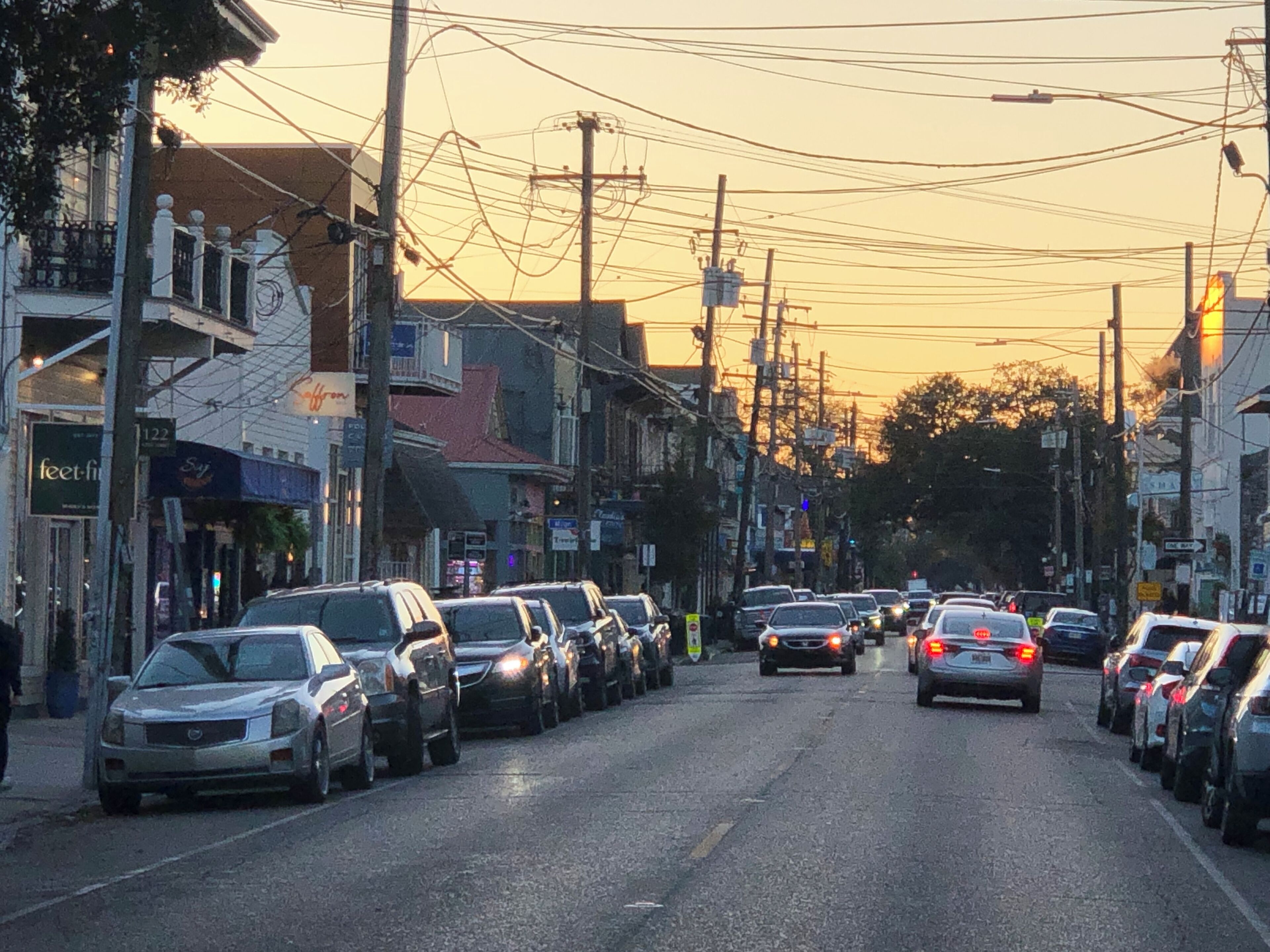 Rua com carros estacionados e edifícios com diversos sinais e fachadas de lojas.