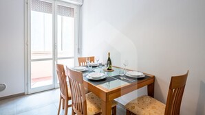 A dining area with a glass table, wooden chairs, and a bottle of champagne.