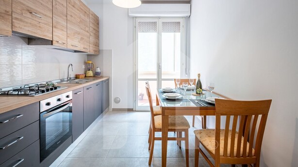 A modern kitchen with wooden cabinets, a gas stove, and a dining area with a table set for two.