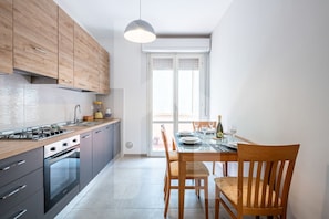 A modern kitchen with wooden cabinets, a gas stove, and a dining area with a table set for two.