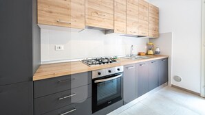 A modern kitchen with wooden cabinets, a gas stove, a sink, and a built-in oven.