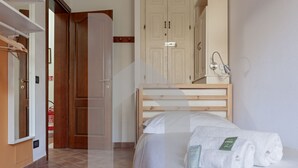 Une chambre d’hôtel avec un lit, une tête de lit en bois, une table de chevet avec une lampe et une armoire.