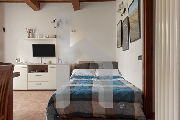 A bedroom with a bed, a TV, a desk, and a chair. - TUSCANY HOUSE is the best solution for any need, close to the center along Viale delle Piaggi and to the Cisanello hospital. A beautiful garden welcomes you in a quiet and residential area with parking space (No ZTL). The independent house is composed by (Pisa)