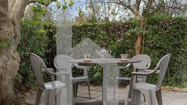 Une table ronde avec quatre chaises, une théière et deux tasses.