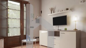 Une cuisine moderne équipée d’un téléviseur, de meubles blancs, d’une petite table et d’une porte en verre dépoli.