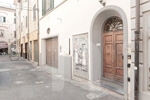 A narrow street with closed shops and a large wooden door with an ornate archway.