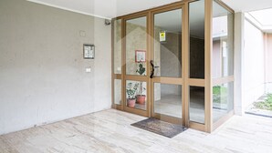 A modern entrance with a glass door, a doormat, and potted plants. - [Homiday] Elegant apartment with wooden finishes in the central area.Relax and enjoy the three bright double bedrooms equipped with air conditioning and heating. Homiday offers the perfect accommodation for those who travel for work or leisure, in the ar (Pisa)