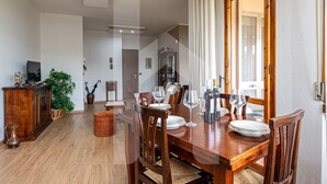 A dining area with a wooden table set for four, surrounded by chairs. A wooden cabinet and a potted plant are visible in the background. - [Homiday] Elegant apartment with wooden finishes in the central area.Relax and enjoy the three bright double bedrooms equipped with air conditioning and heating. Homiday offers the perfect accommodation for those who travel for work or leisure, in the ar (Pisa)