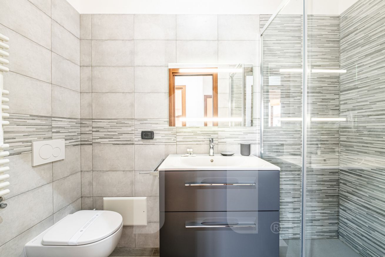 Un baño moderno con inodoro, lavamanos y espejo.