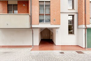 Une entrée d’immeuble avec un portail en métal, un mur en briques et un sol carrelé.
