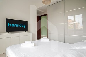 Une chambre d’hôtel avec un lit, une télévision et une armoire.