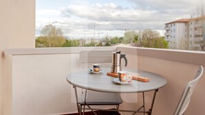 Ein Balkon mit rundem Tisch, Stühlen, einem Wasserkocher und einer Tasse.