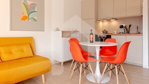 Eine moderne Küche mit Esstisch, orangefarbenen Stühlen und einer Couch.