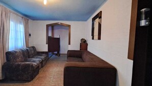 A hallway with a sofa set, a wooden door, and a wall-mounted light fixture. - Hotel Cordillera Cabildo (Cabildo)