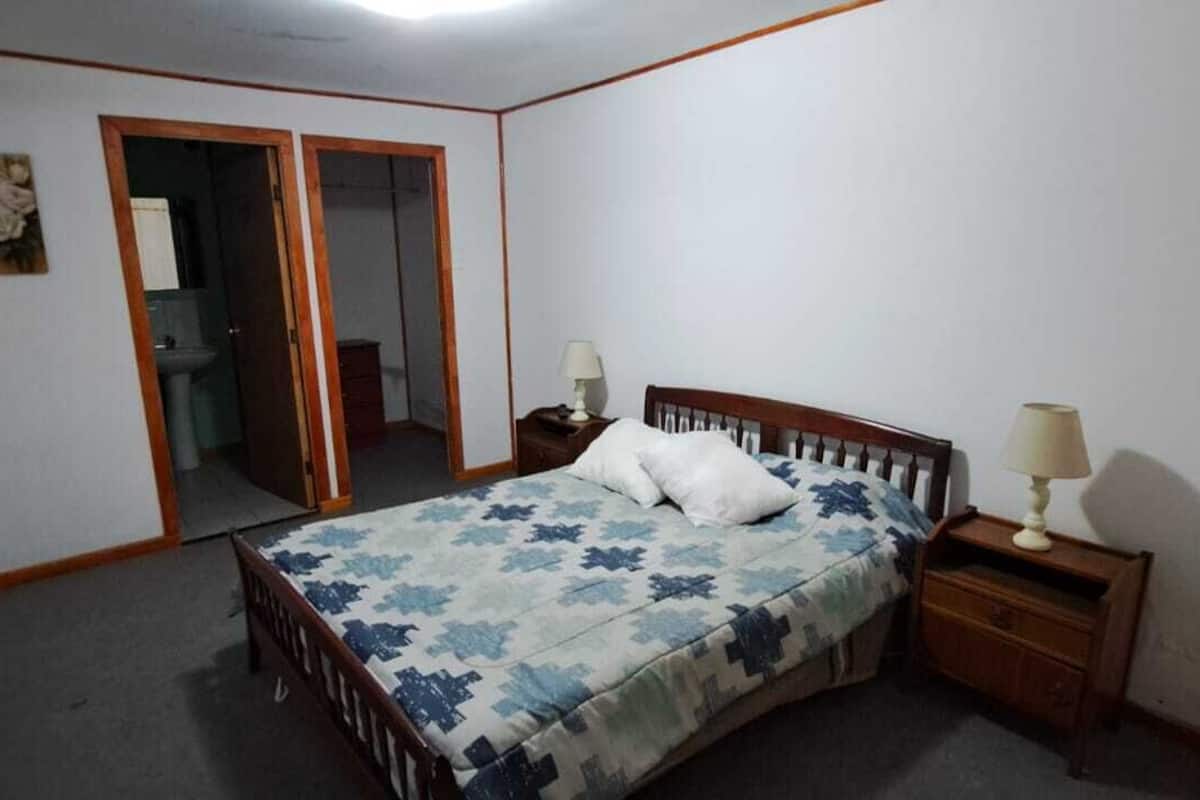 Een slaapkamer met een bed, nachtkastjes, een spiegel en een televisie aan de muur.