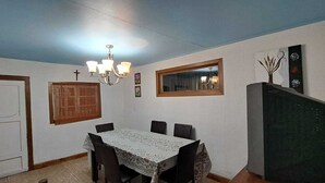 A dining area with a table, chairs, a chandelier, a window, and a door. - Hotel Cordillera Cabildo (Cabildo)