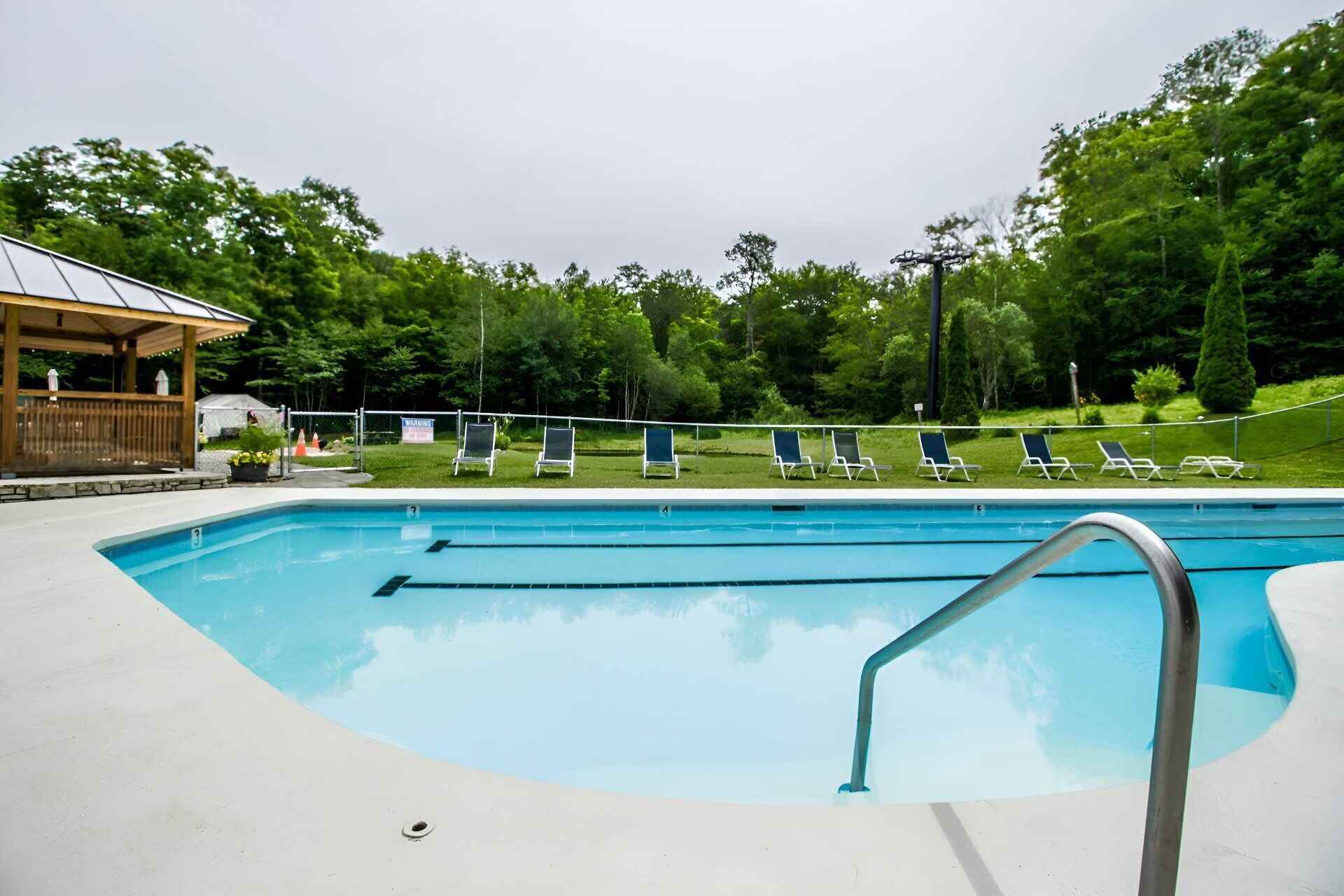 Una piscina con sillas de descanso y un pabellón.