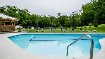 Una piscina con sillas de descanso y un pabellón.