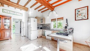 Una cuina moderna amb bigues de fusta, un frigorífic integrat, una placa de cocció i un rentaplat.