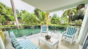 A sunlit outdoor seating area with a pool view, featuring striped cushions and white furniture. - Paradise in Las Terrenas. Exclusive villa with pool (Las Terrenas)