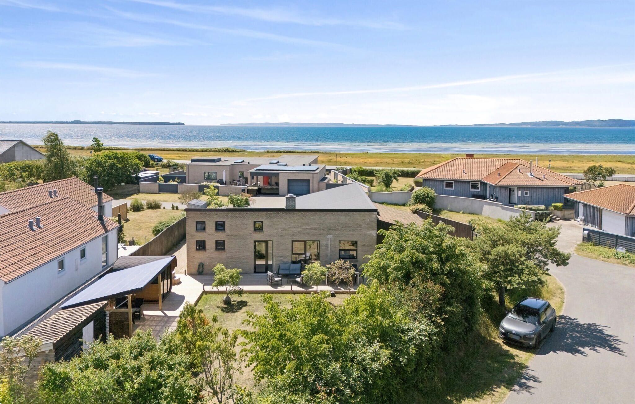 A residential area with houses, a car, and a view of the sea.