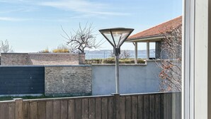 Een modern buitengebied met een metalen lantaarnpaal, een houten hek en uitzicht op de zee.