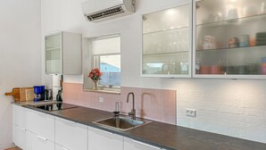 Een moderne keuken met een roestvrijstalen spoelbak, witte kasten, een ingebouwd raam en een airconditioning.