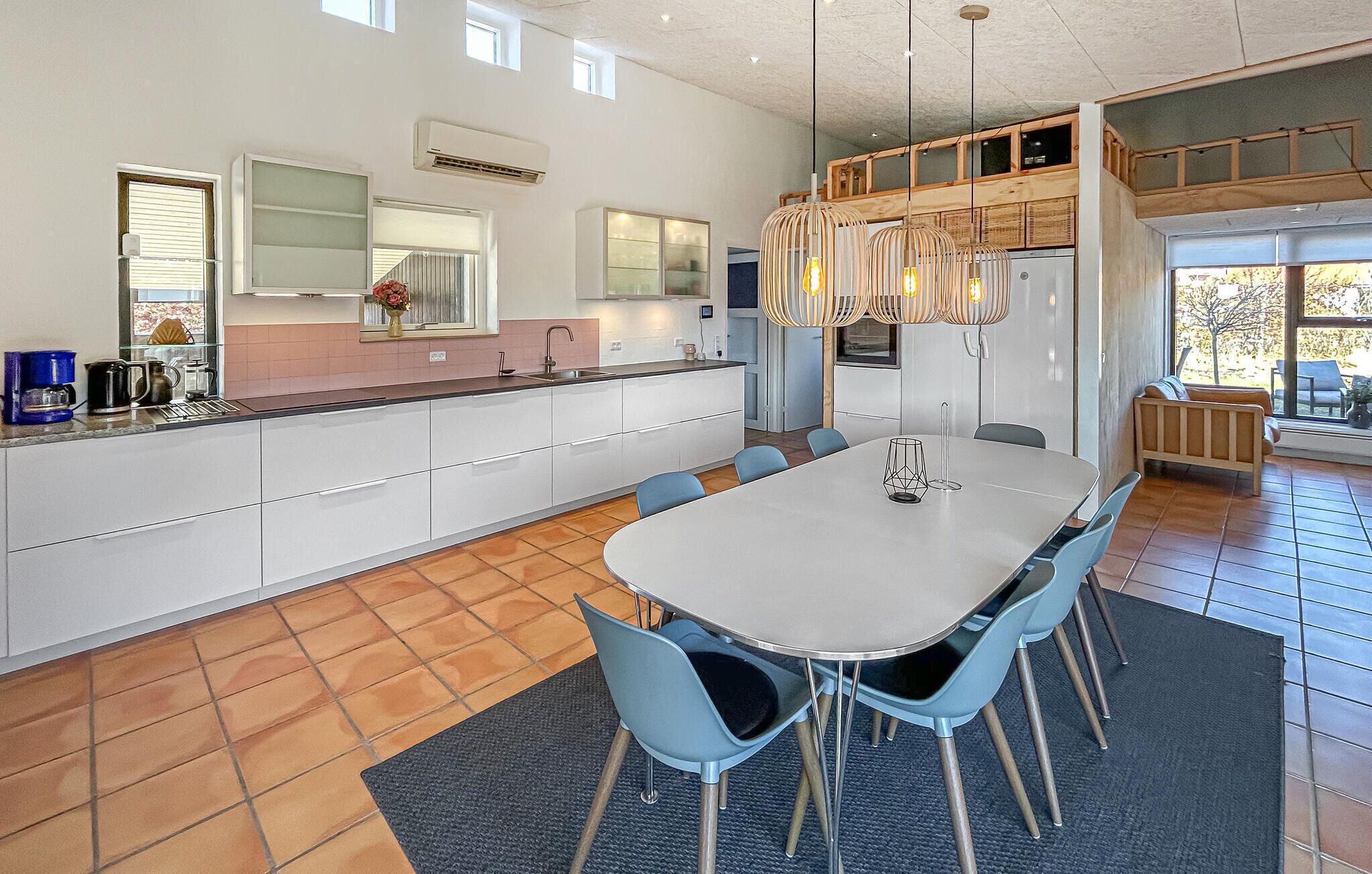 A modern kitchen with white cabinets, a central island, and a dining area with a table and chairs.