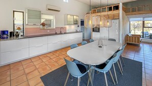 Een moderne keuken met witte kastjes, een centraal kookeiland en een eethoek met een tafel en stoelen.