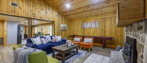 A wooden interior with a sofa, chairs, a coffee table, and a fireplace.