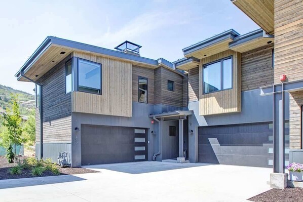 A modern two-story house with a garage, large windows, and a flat roof.