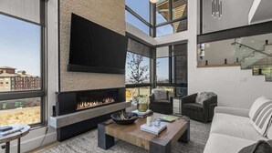A modern living room with a fireplace, large windows, and a staircase. - Abode at Moose Ridge, private hot tub, ski access, modern home (Park City)
