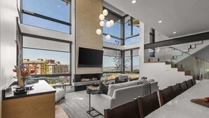 A spacious living area with a fireplace, large windows, and a modern staircase. - Abode at Moose Ridge, private hot tub, ski access, modern home (Park City)