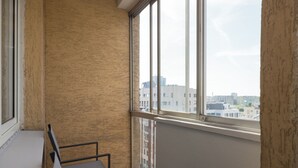 Et værelse med et stort vindue, en metalstol og en væg med struktur.