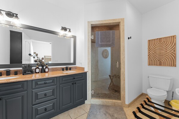 A modern bathroom with a large vanity, a glass shower enclosure, and a toilet.