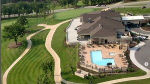 Un campo de golf con piscina y canchas de tenis.
