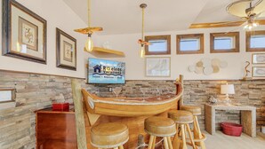 Un espace bar doté d’un comptoir en bois en forme de bateau, de tabourets et d’un téléviseur diffusant des images de « RO-elsens Vacations ».