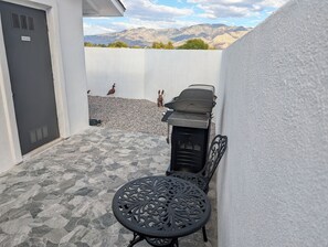 Une terrasse avec un barbecue, une porte donnant sur une pièce utilitaire et une table décorative.