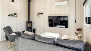 Un salon moderne avec un canapé gris, un téléviseur, une cheminée et une petite table.
