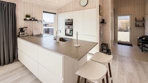 Une cuisine moderne avec un îlot central, des meubles blancs, un évier et une horloge au mur.