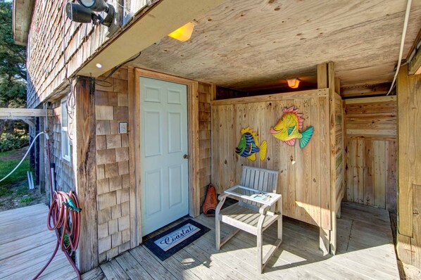 Une cabane en bois avec une porte, un banc et un motif décoratif représentant un poisson sur le mur.