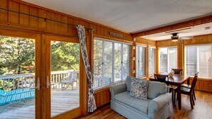 A cabin interior with a wooden deck, a sofa, a dining table, and a sign reading "Salty Air Retreat".