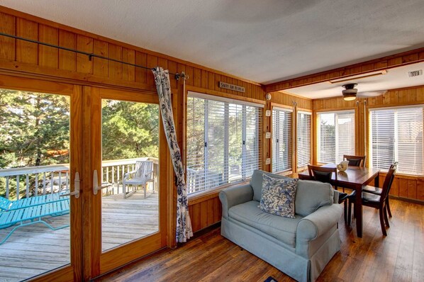 A cabin interior with a wooden deck, a sofa, a dining table, and a sign reading "Salty Air Retreat".