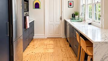 A modern kitchen with wooden flooring, stainless steel appliances, and a marble countertop.