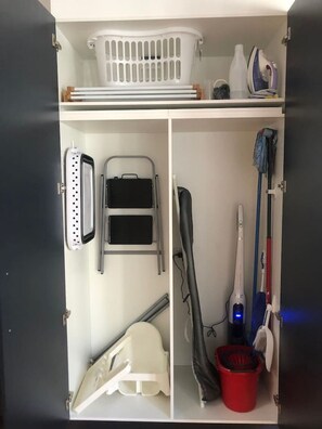Ein Lagerraum mit Wäschekorb, Bügelbrett, Bügeltuch, Bügelgestell und einem Mop.