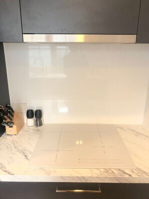 Eine Küche mit einem modernen Induktionskochfeld, einer Marmorarbeitsplatte und einem eingebauten Backofen.
