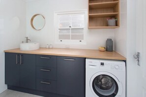 Un baño moderno con lavamanos, espejo, ventana y lavadora.