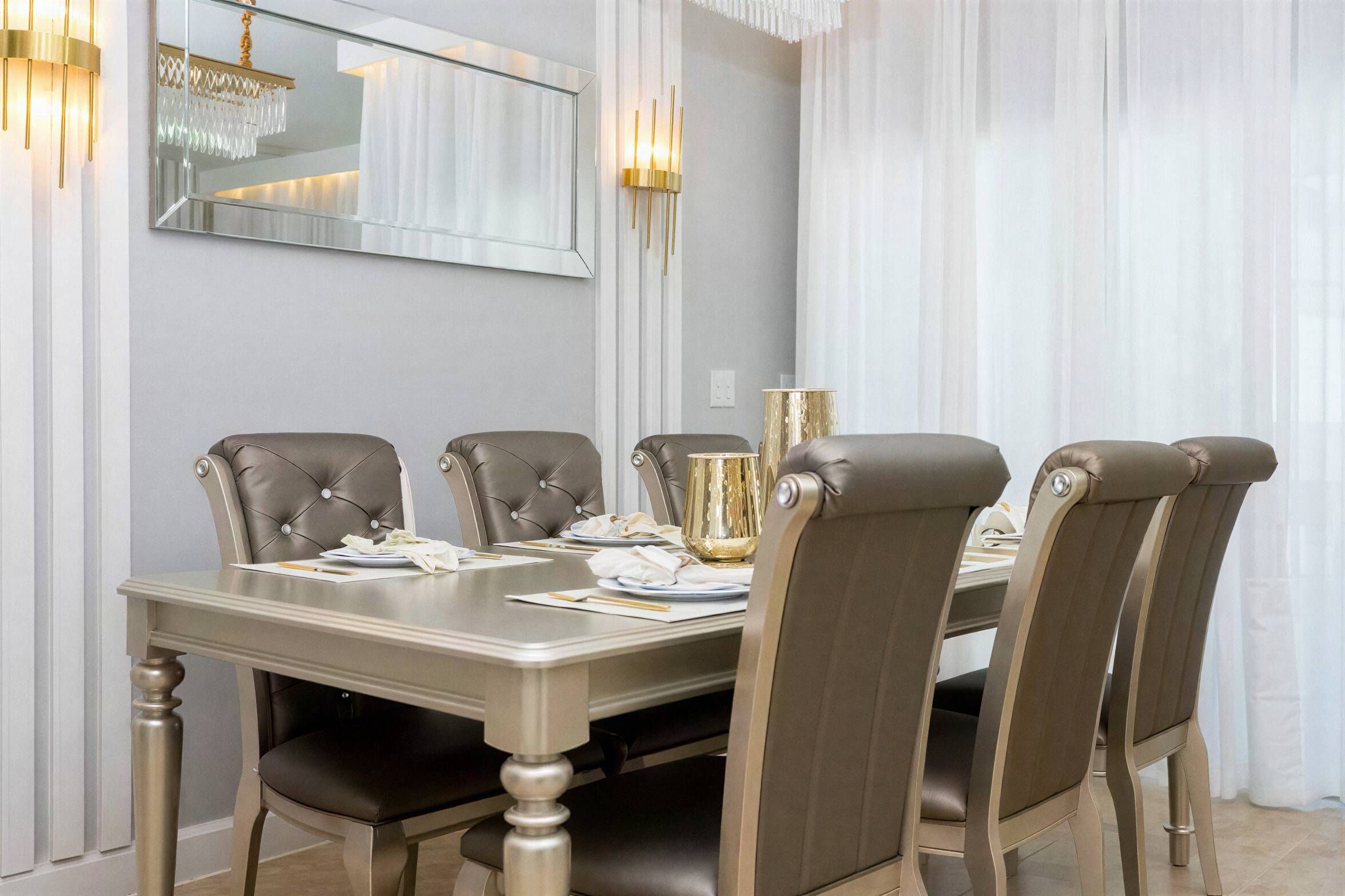Ein Esszimmer mit einem rechteckigen Tisch, sechs Polsterstühlen und einer Chandelüster.